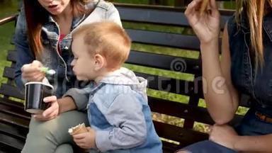 孩子坐在长凳上<strong>吃</strong>冰淇淋。 年轻的女人和孩子正在长凳上的公园里<strong>吃</strong>冰淇淋。 <strong>青</strong>年
